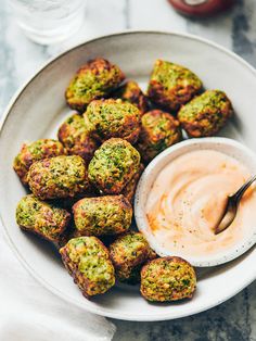 a white plate topped with broccoli bites and dip