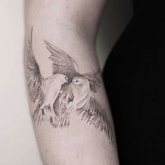 a person with a tattoo on their arm and two birds in the air above them