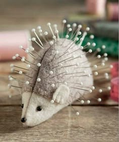 a toy hedgehog with white spikes on its head sitting next to some thread spools