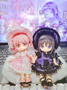 two dolls sitting on top of a keyboard