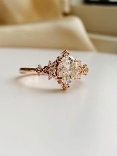 a diamond ring sitting on top of a white table next to a chair and window