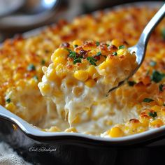 a spoonful of macaroni and cheese with parsley on top is being lifted from a casserole dish