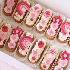 a box full of decorated cookies with pink and white frosting on them, sitting on a table