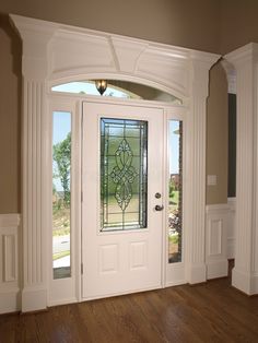 an empty entryway with wooden floors and white doors