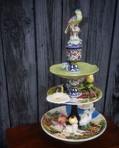 three tiered plates with birds on them and other decorative items in front of a wooden wall