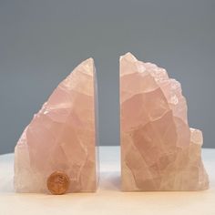 two pieces of pink rock with a penny on the top one is shaped like a mountain