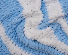 a blue and white crocheted blanket laying on top of a bed