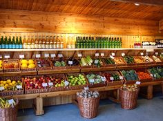 a store filled with lots of different types of fruits and vegetables next to bottles of wine