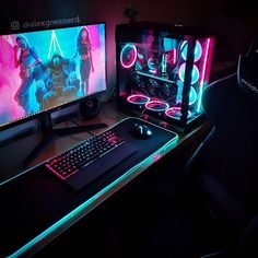 a computer desk with a keyboard, mouse and monitor lit up by neon lights in the dark