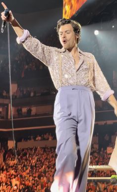 the man is performing on stage with his hands in the air while holding a microphone