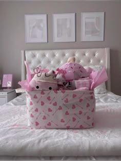 a pink and white bed topped with a stuffed animal in a basket on top of it