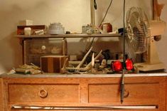 an old dresser with many items on it and a fan sitting on top of it