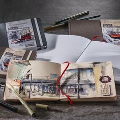 an open book sitting on top of a table next to some pens and pencils