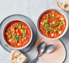 two bowls of soup with bread on the side