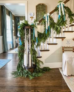 the staircase is decorated with greenery and blue ribbon for christmas time as well as wreaths