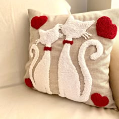 a white couch with a red and white cat pillow on it's back side