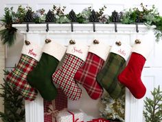 christmas stockings hanging from a mantel decorated with holly and red, white and green stocking