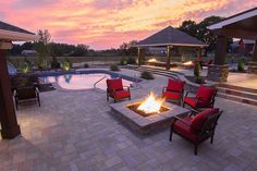 a fire pit in the middle of a patio next to a swimming pool at sunset