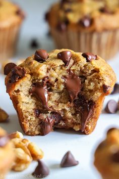 a muffin with chocolate chips and nuts on the top is sitting on a white surface