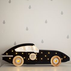 a wooden toy car with lights and raindrops on the wall next to it