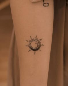 a woman's arm with a small sun tattoo on the left side of her leg