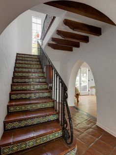 an arched staircase leads up to the second floor with tile floors and handrails