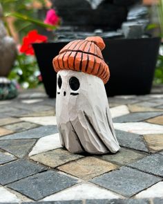 a ceramic figurine with a hat on it's head sitting on the ground