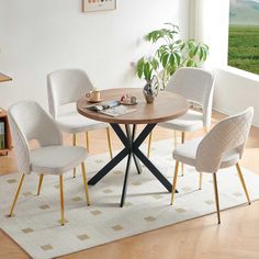 a dining table with four chairs and a potted plant in the corner next to it