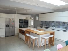 a kitchen with white cabinets and wooden counter tops next to an island in the middle