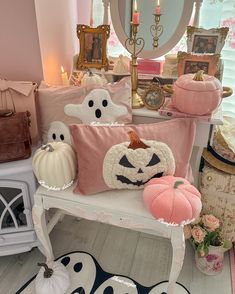 a white bench topped with lots of pillows and pumpkins next to a mirror on top of a wooden floor