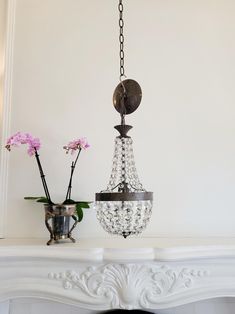 a chandelier hanging from the ceiling next to a vase with flowers in it