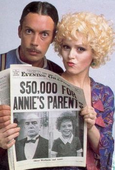 the man and woman are holding up a news paper that says $ 50, 000 for annie's parents