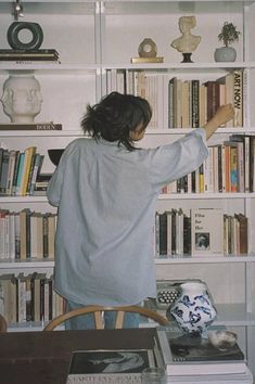 a woman standing in front of a book shelf filled with books