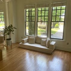 a living room filled with furniture and windows next to a hard wood floored floor