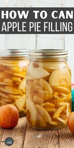 two jars filled with apple pie filling on top of a wooden table next to apples