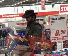 a man in a hat is holding a shopping cart and looking at the items for sale