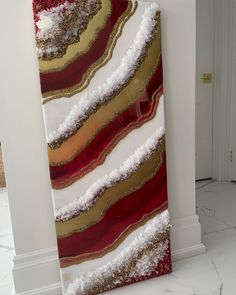 a painting is hanging on the wall next to a white door with a red and gold stripe design