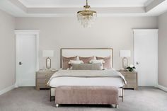 a bedroom with a bed, dressers and a chandelier