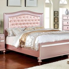 a pink bed sitting on top of a wooden floor next to a dresser and mirror