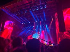 the stage is lit up with red and blue lights, while people are seated in front of it