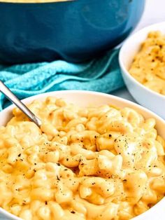 two bowls filled with macaroni and cheese on top of a blue table cloth