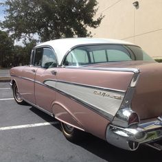 an old pink car parked in a parking lot