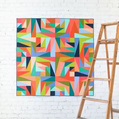 a ladder next to a painting on a brick wall with an orange and blue design