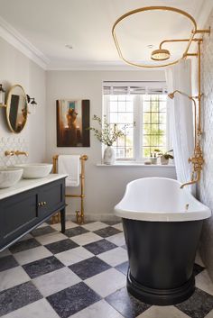 a bathroom with black and white checkered flooring, two sinks, an oval bathtub