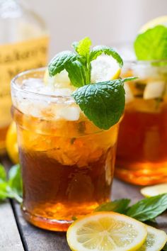 two glasses filled with iced tea, lemon and mint garnish on a wooden table