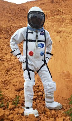 an astronaut is standing in the dirt with his hands on his hips