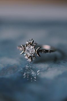 a diamond ring sitting on top of a blue surface with the moon in the middle