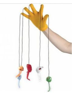 a hand with yellow gloves is holding three small toy animals hanging from strings in front of white background