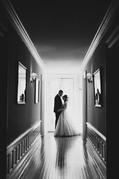 a bride and groom are standing in the hallway at their wedding reception, black and white photograph