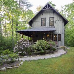 an old log house with flowers in the front yard